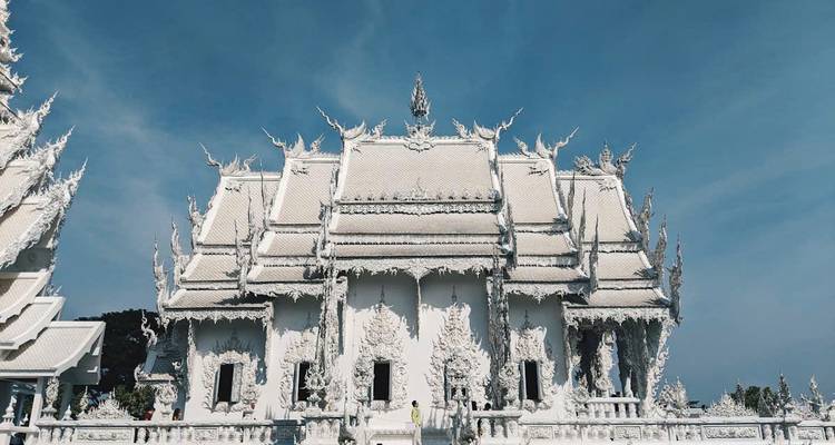 A white temple with detailed artistry under a clear blue sky.