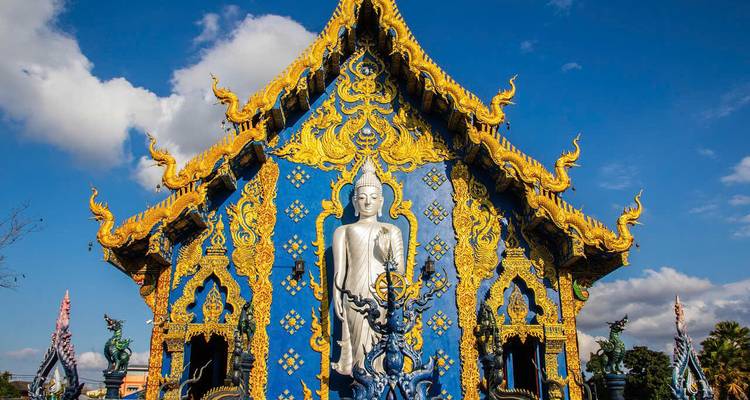 A blue temple with a white Buddha statue at its entrance.