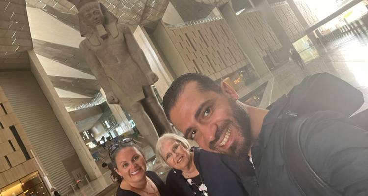 Photo de groupe avec une statue égyptienne antique massive à l'intérieur d'un bâtiment d'apparence moderne.