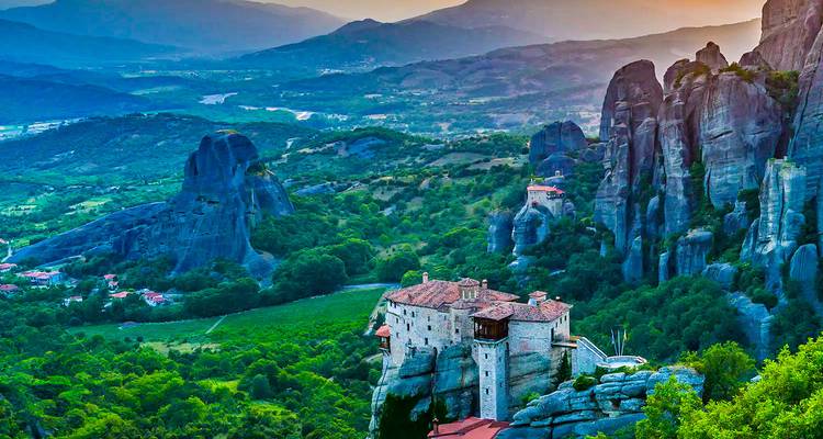 Dramatisch uitzicht over Meteora kloosters gelegen bovenop torenhoge rotspilaars bij zonsondergang