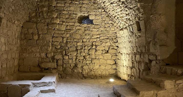 Intérieur d'une ancienne structure en pierre avec des murs texturés et de petites fenêtres.