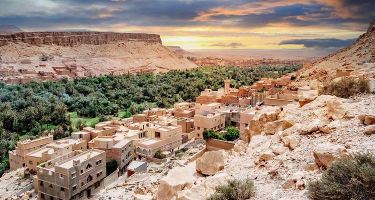 Una vista impresionante de un pueblo marroquí rodeado de terreno escarpado y palmeras.
