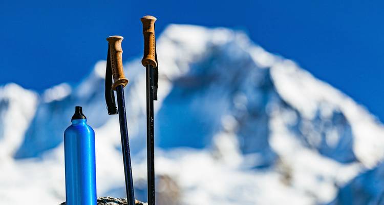 Bâtons de randonnée et bouteille d'eau avec une montagne en arrière-plan.