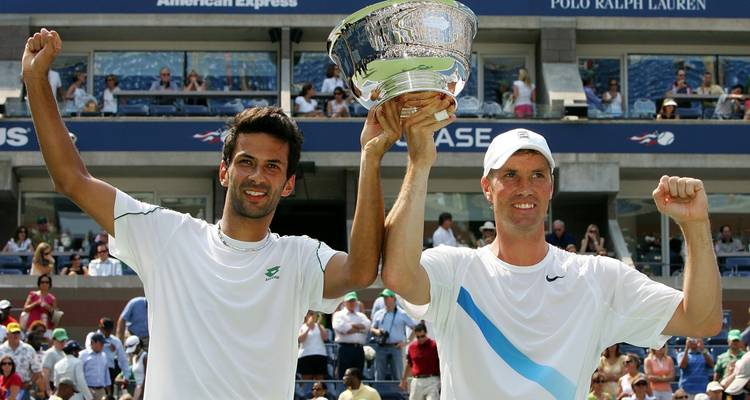 Twee tennissers die een trofee vasthouden en een overwinning vieren voor een menigte.