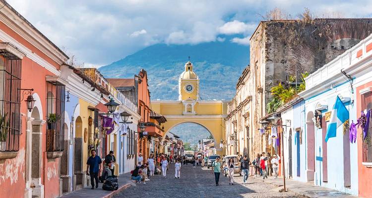 L'emblématique Arche jaune Santa Catalina encadrant un volcan lointain le long d'une animée rue pavée d'Antigua