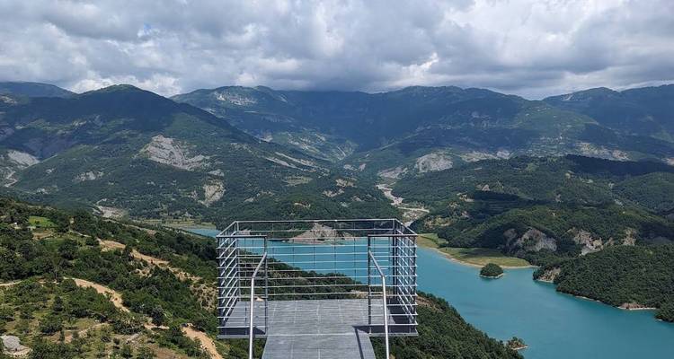 View of a modern platform overlooking a lake and mountains.