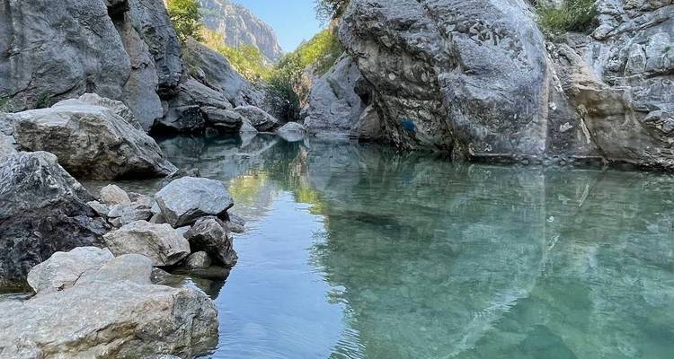 Rocky river with clear water, surrounded by cliffs.