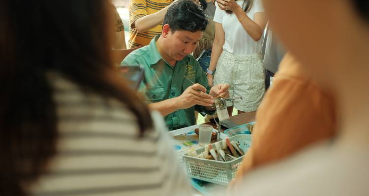 Homme impliqué dans une activité culinaire avec un groupe de personnes autour.