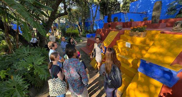 Grupo de personas escuchando a un guía en un entorno exterior colorido.