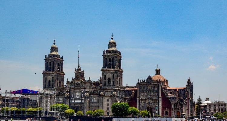 Una gran catedral colonial en una plaza urbana con un cielo azul despejado.