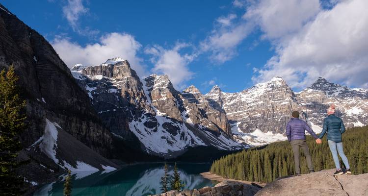 Couple se tenant la main avec vue sur le lac Moraine et les montagnes.