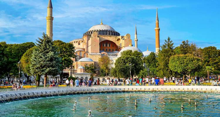 Menschenmengen versammeln sich an einem hellen Tag um einen großen Brunnen vor der Hagia Sophia