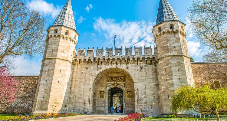 Großes Steineingangstor mit Zwillingstürmen des Topkapi-Palastes unter blauem Himmel