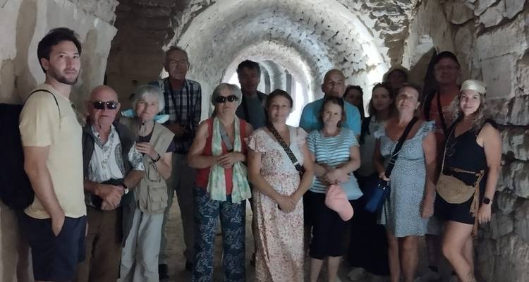 Groep toeristen die in een gewelfde stenen gang staan.