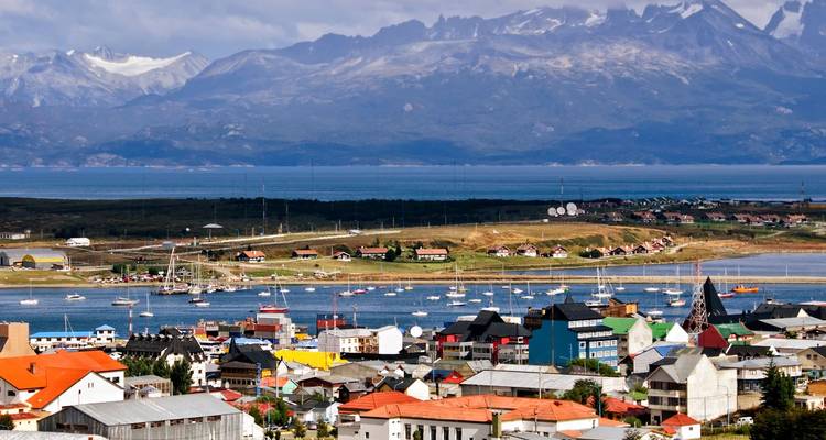 Los tejados coloridos de Ushuaia bordean un puerto helado respaldado por picos escarpados cubiertos de nieve.