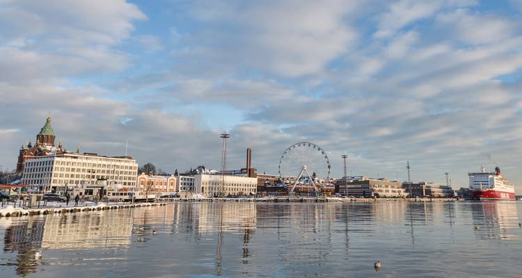 Helsinki’s waterfront with Uspenski Cathedral, ferris wheel and ships mirrored in calm water.