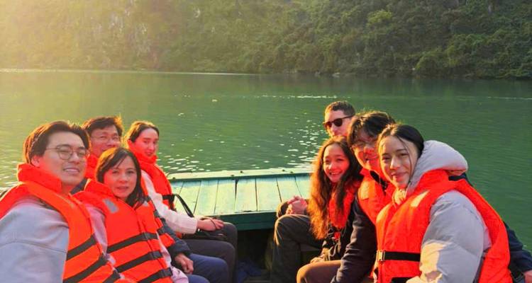 Group wearing orange life jackets on a boat cruising a green lagoon in late afternoon light.