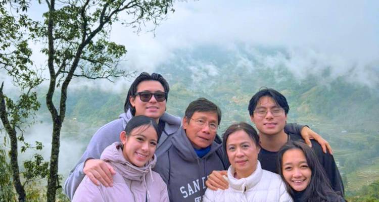 Family group smiles with misty terraced mountains in the background.