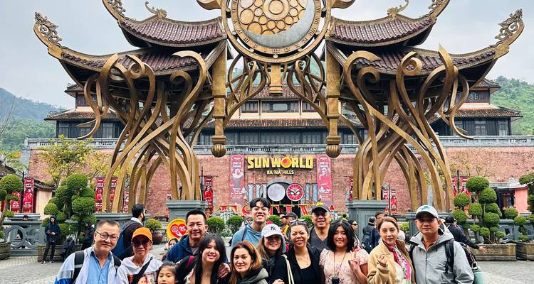 Large tour group poses before the ornate Sun World Ba Na Hills entrance arch.