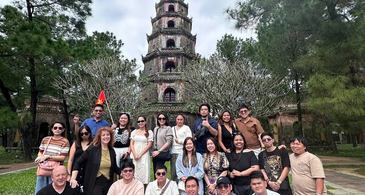 Großes Gruppenfoto vor der Thien Mu Pagoda, umgeben von blühenden Bäumen.