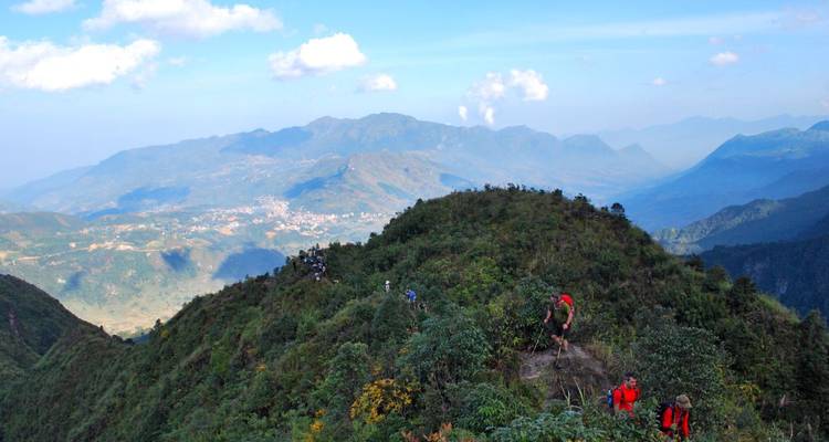Wanderer auf einem Bergpfad mit üppigem Grün und Bergen.