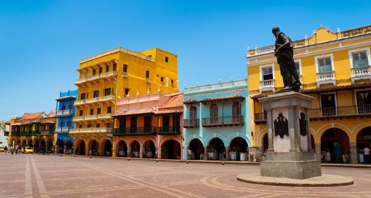 Kleurrijke gebouwen in koloniale stijl rondom een standbeeld in Cartagena, Colombia.