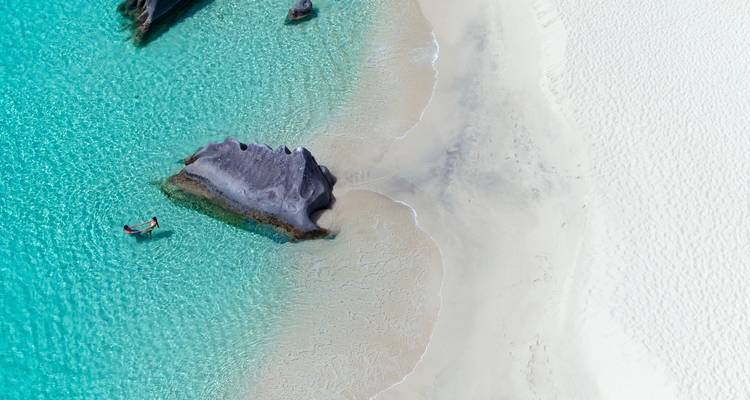 Vista aérea de una hermosa playa con agua azul cristalina y rocas.