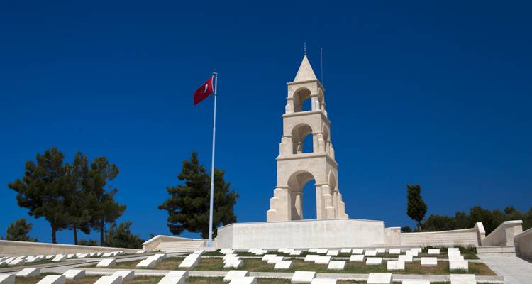 Een gedenktoren met een vlag onder heldere blauwe luchten in Çanakkale.