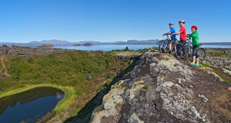 Grupo de ciclistas disfrutando de una vista panorámica desde una colina rocosa.
