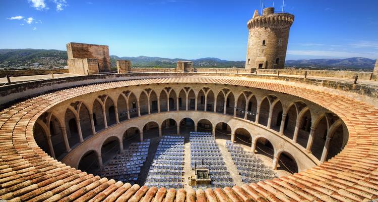 Historisch kasteel met een ronde binnenplaats en een schilderachtig landschap op de achtergrond.