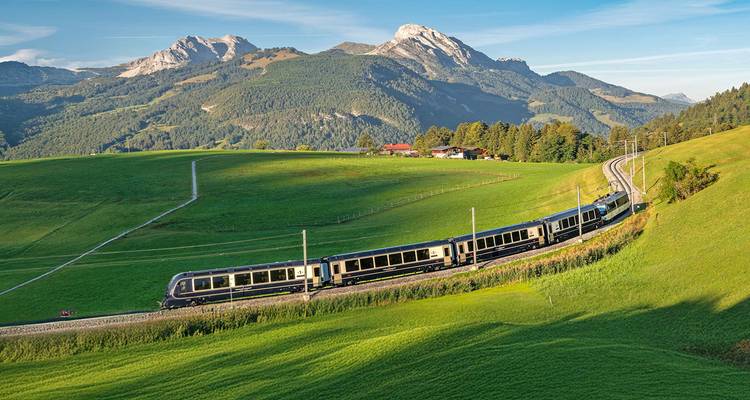 Train traversant un paysage montagneux verdoyant.