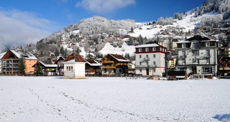 Verschneite Landschaft mit einer kleinen Stadt und schneebedeckten Hügeln.