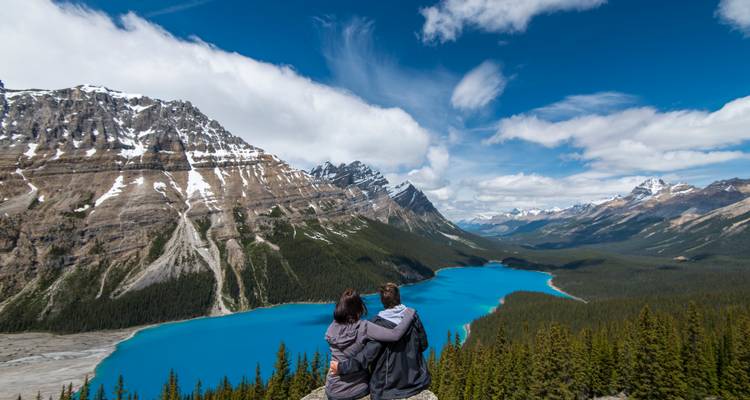 Pareja contemplando un lago turquesa y montañas.