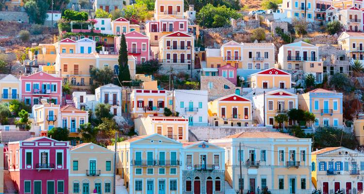 Mosaïque vibrante de maisons néoclassiques aux couleurs pastel empilées sur une colline méditerranéenne ensoleillée