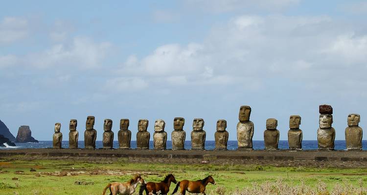 Reihe von Moai-Statuen auf der Osterinsel mit dem Ozean im Hintergrund.
