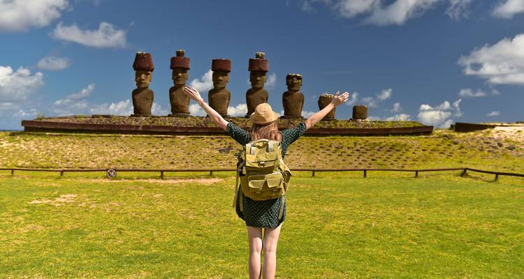 Person mit Rucksack vor Moai-Statuen auf der Osterinsel.