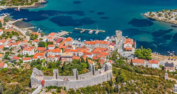 Vue aérienne d'une ville historique au bord de la mer entourée d'une muraille fortifiée.