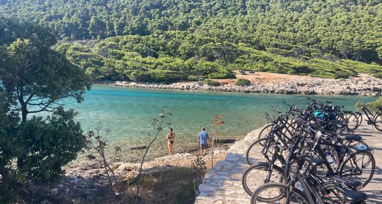 Vélos stationnés près d'un magnifique rivage turquoise avec des personnes à proximité.