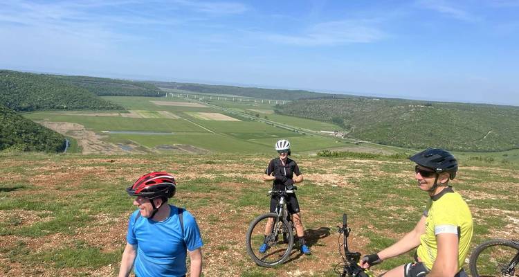 Groupe de cyclistes sur une colline avec une vue panoramique sur la vallée.