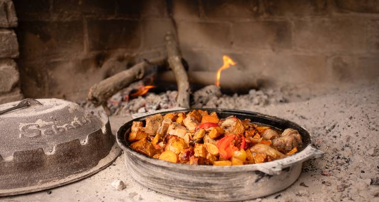 Plat traditionnel cuisinant sur un feu ouvert.