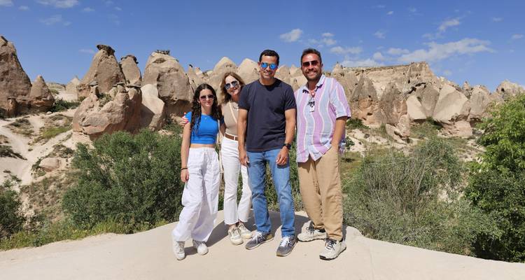 Cuatro personas posando con formaciones rocosas al fondo.