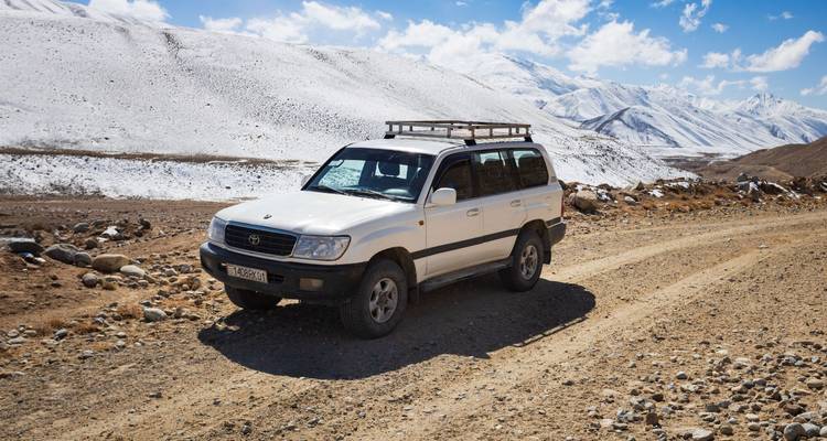 White SUV on a mountainous dirt road.