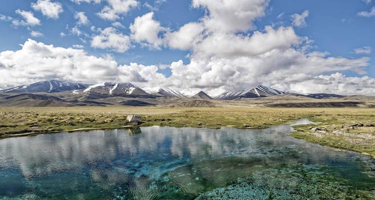 Reflective lake with snowy mountains in the background.