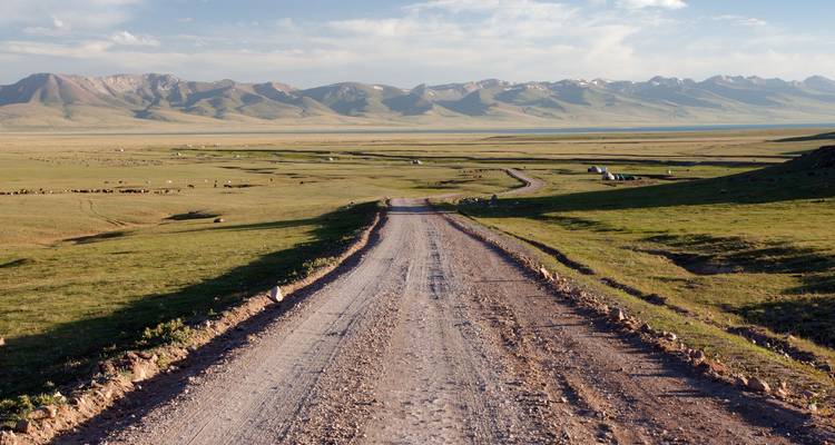 Dirt road leading through vast open plains.