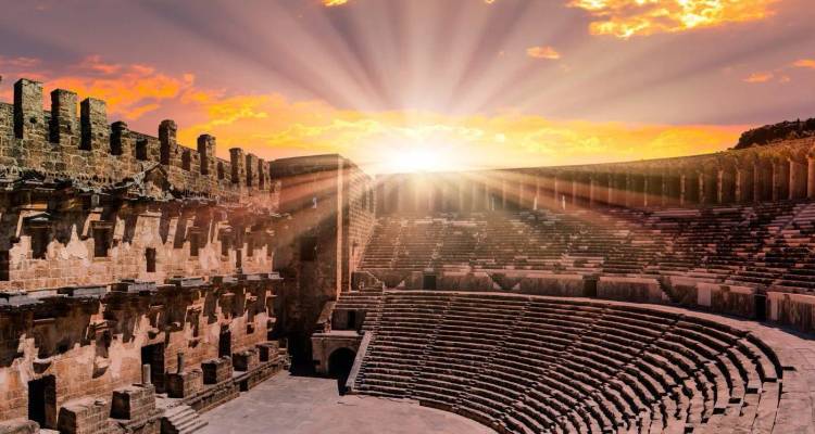 Sonnenstrahlen strömen bei Sonnenuntergang in ein gut erhaltenes römisches Amphitheater.