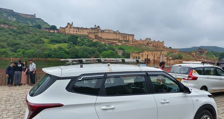Vista del Fuerte de Ámbar en una colina bajo cielos nublados con SUVs estacionados y turistas en primer plano