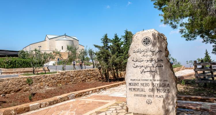Monument en pierre au mont Nébo avec une église en arrière-plan.