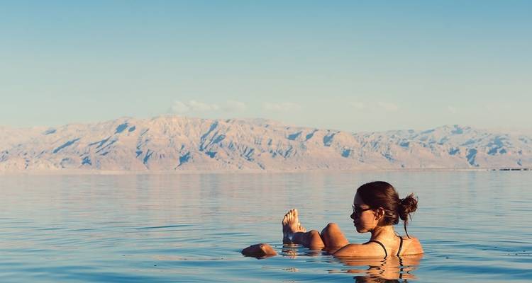 Femme flottant dans la mer Morte avec vue sur les montagnes.