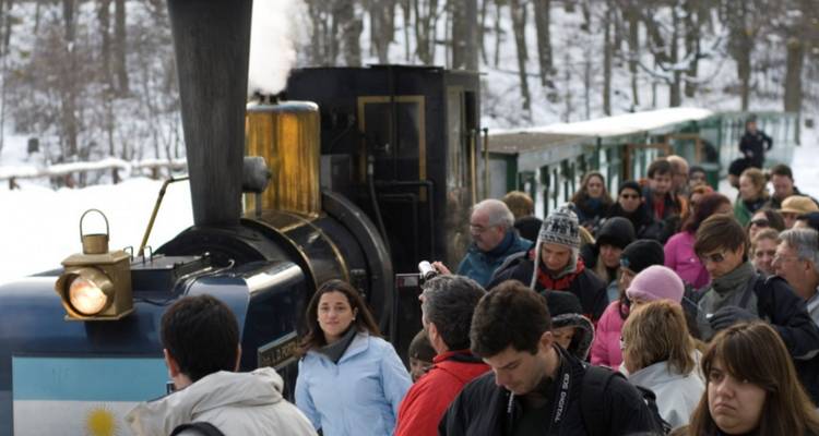 Crowd of people around a vintage train in a snowy setting.