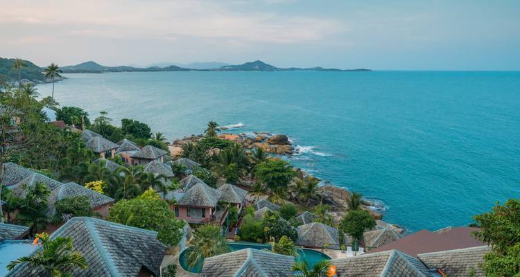 Vue côtière avec villas parmi une végétation luxuriante.